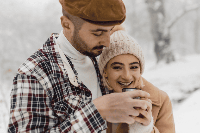 Cozy winter couple outdoor, smiling woman and man in warm clothing enjoying snowy scenery, romantic moment, hot drink, stylish winter fashion, love and happiness, The Solemn Sir branding, lifestyle photography.
