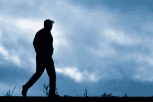 Silhouette of a man walking outdoors against a cloudy sky, evoking themes of solitude and reflection, perfect for inspiring imagery on personal growth, mindfulness, and life's journey.