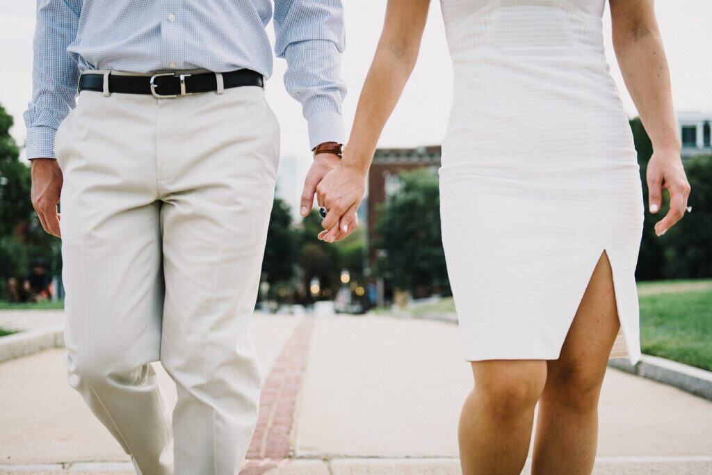 Elegant couple holding hands during a romantic outdoor walk, emphasizing connection and love in a stylish, modern setting for The Solemn Sir.