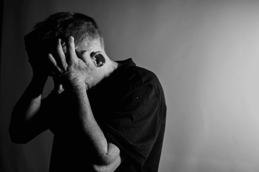 Desperate man holding his head in despair, black and white photo emphasizing emotional distress and mental health struggles.