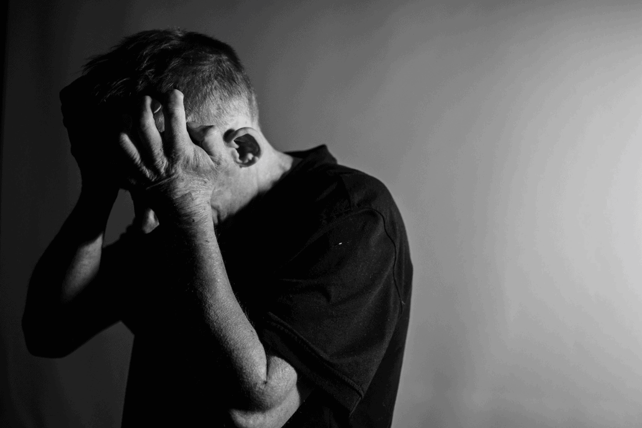 Desperate man holding his head in despair, black and white photo emphasizing emotional distress and mental health struggles.