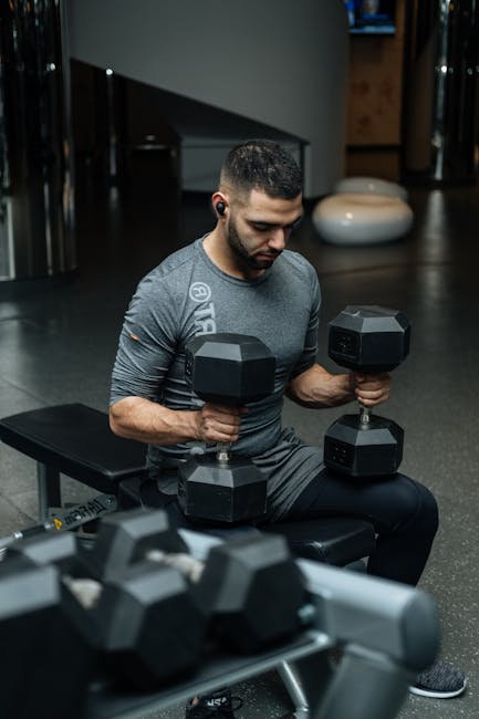 Adult man lifting dumbbells in a gym, focused on strength training workout.