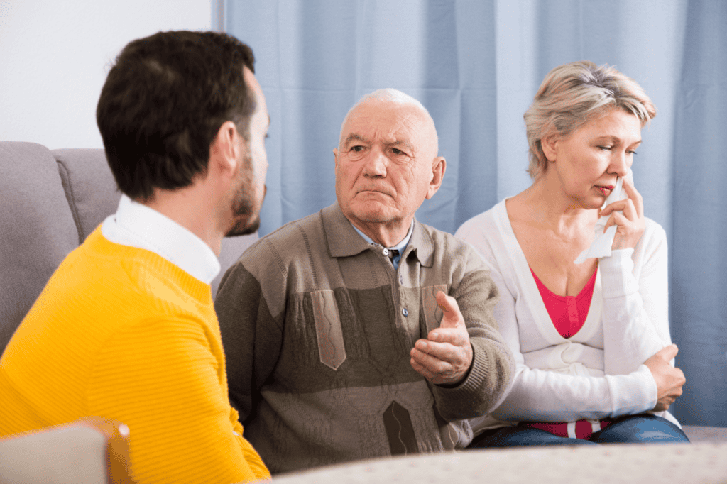 Distraught elderly couple talking to a counselor about emotional or family issues in a therapy or support session.