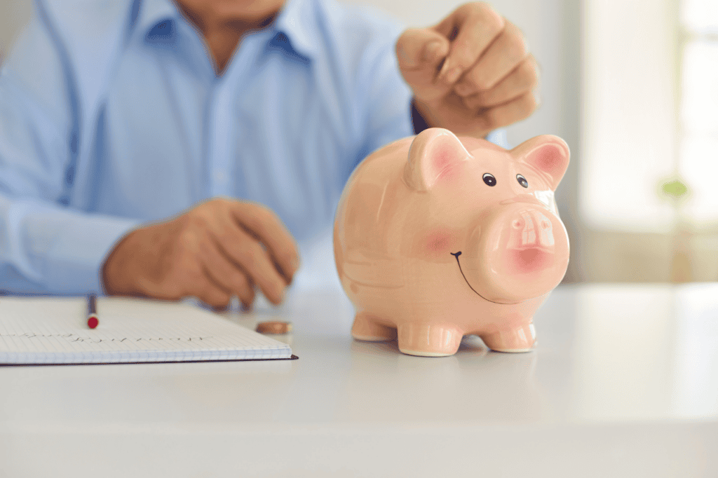 Pink ceramic piggy bank with a cheerful smile on a white table, emphasizing savings and financial planning.