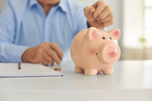 Pink ceramic piggy bank with a cheerful smile on a white table, emphasizing savings and financial planning.