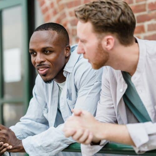 Friendly men having a conversation outdoors on a sunny day, reflecting connection and dialogue in a casual setting.