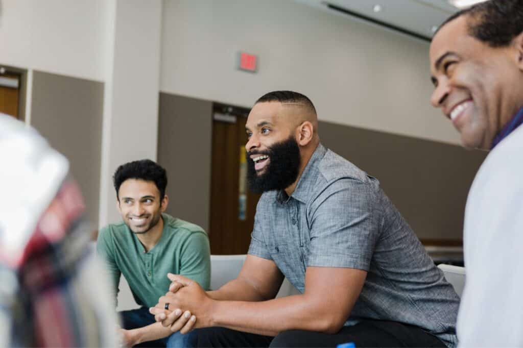 Professional diverse group of men engaged in a lively discussion at a modern corporate meeting. Focus on teamwork, collaboration, and workplace diversity.