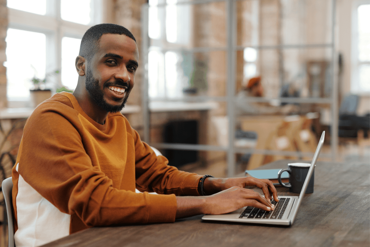 Young man working on a laptop in a modern, cozy office space with natural light.
