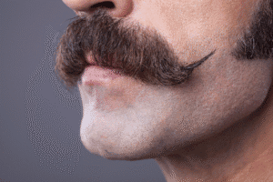 Luxurious mustache and smooth skin close-up, emphasizing grooming and facial hair styling for men’s grooming tips and beard care.