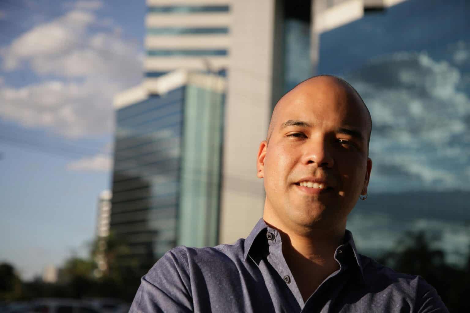 Smiling bald man in front of modern buildings in Brasília, Brazil.