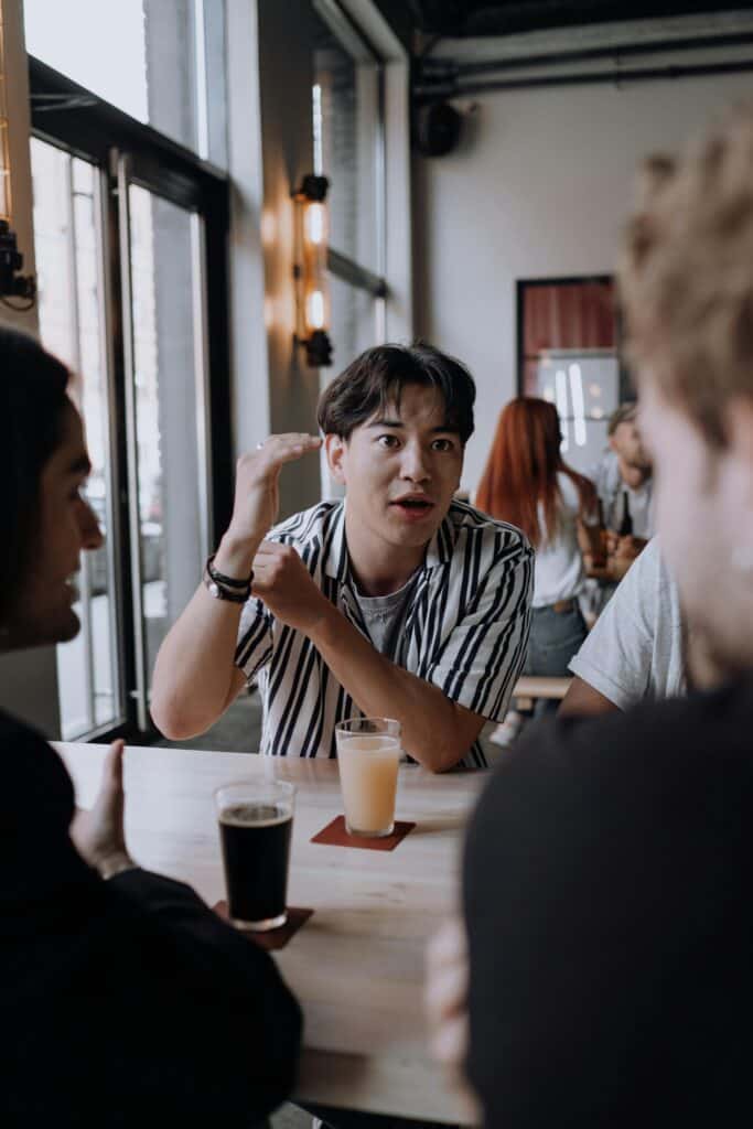 A group of friends enjoying drinks and a lively conversation at an indoor pub setting.