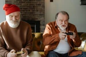 Two elderly men having fun playing video games on the couch.