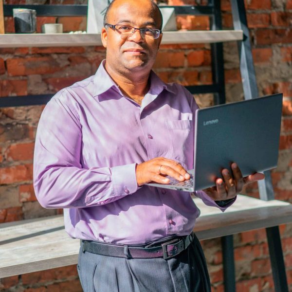 Confident man standing in office holding laptop. Business and technology concept.